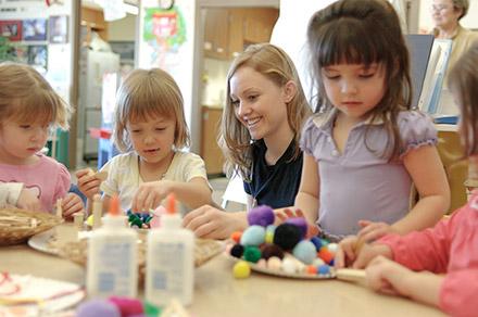 A student volunteer works with children on an art project at the Child Development Center Laboratory